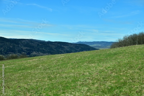 Obraz na płótnie Landscape scenery green grass, brown forests and blue sky w salonie