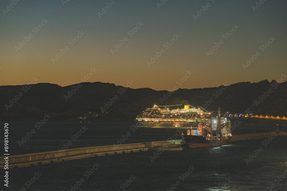 Modern cruiseship cruise ship liner Diadema at sea with coast line during twilight sunset blue hour Modern cruiseship cruise ship liner Diadema at sea with coast line during twilight sunset blue hour