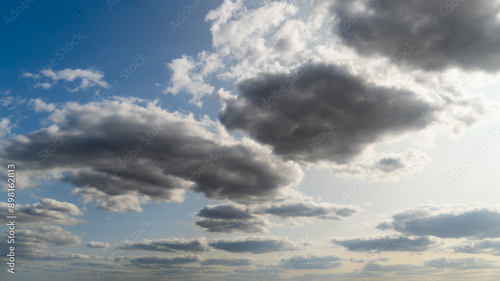 Fototapeta premium beautiful blue sky with dark dramatic cumulus clouds and sunlight for abstract background