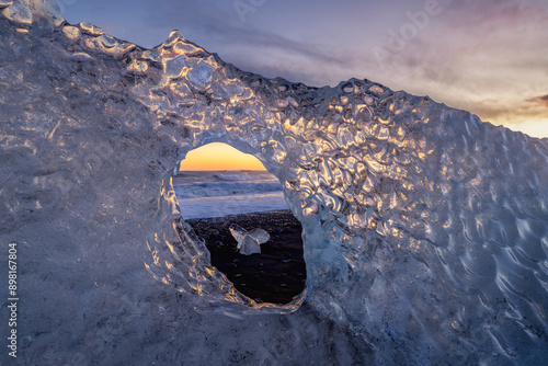 Ice fragment with a hole on a black sand beach in Iceland photo