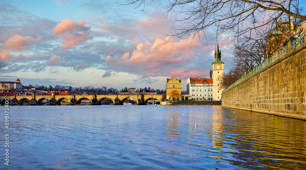 Naklejka premium Prague, Czech Republic. Panoramic view at the Charles Bridge on Vltava river. Dramatic sky with clouds and beautiful medieval architecture. Popular european travel destination.