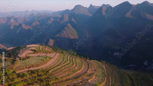 This footage captures the breathtaking terraced rice fields and majestic mountains of Ha Giang, North Vietnam.The shot showcases the terraced fields illuminated by the warm light of the setting sun.