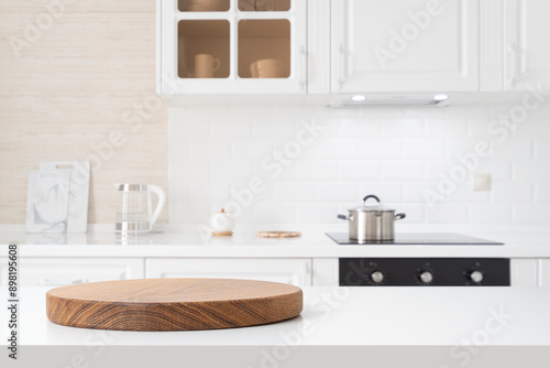 Round wooden pedestal on white table with copy space and defocused kitchen counter background
