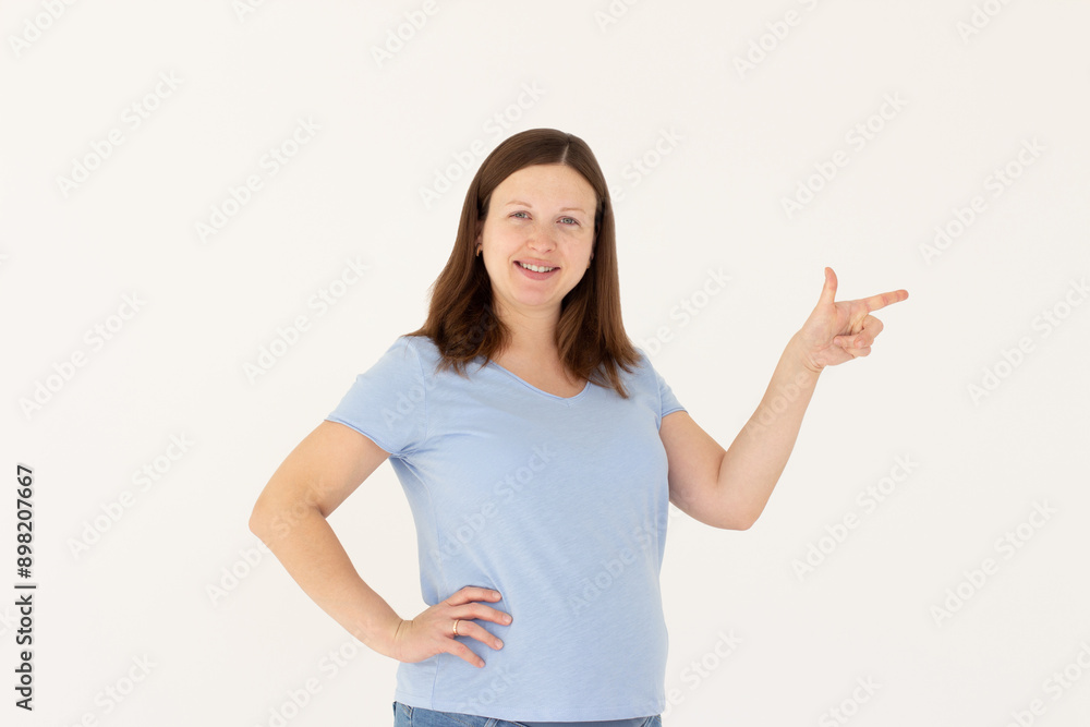 Hey look. Smiling pretty female model pointing finger right at empty space and inviting to check it out, showing advertisement on white background. Hey look. Smiling pretty female model pointing finger right at empty space and inviting to check it out, showing advertisement on white background.