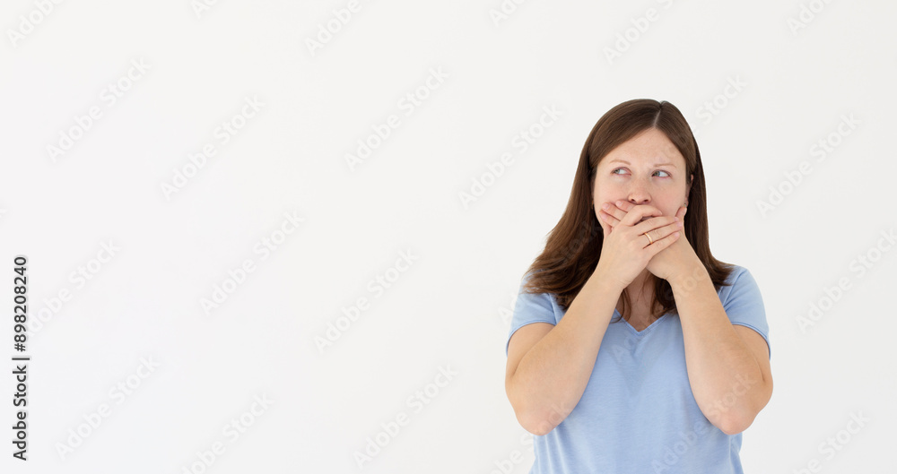 Portrait of a shocked young girl in blue t-shirt looking aside with mouth covered isolated over white background Portrait of a shocked young girl in blue t-shirt looking aside with mouth covered isolated over white background