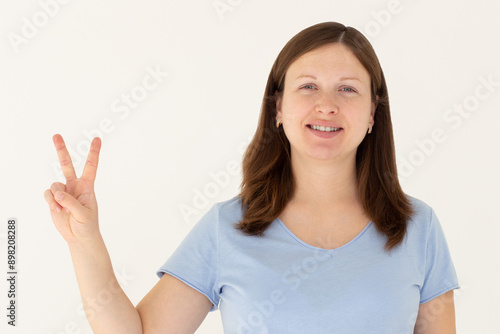 Wallpaper Mural Young caucasian smiling happy friendly woman in stylish casual blue t-shirt show victory v-sign gesture isolated on white background studio portrait People lifestyle concept Torontodigital.ca