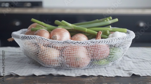   A towel and wooden table support an array of vegetables, including onions, asparagus, and green beans, contained within a mesh bag