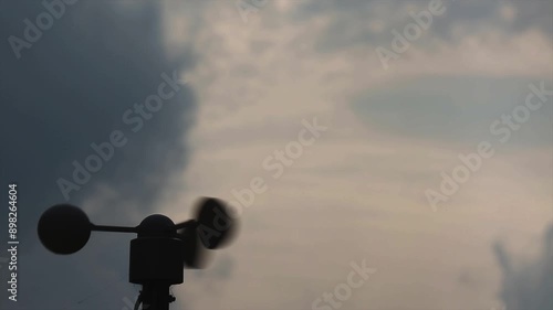 A silhouette of a spinning anemometer against a pastel yellow and blue sky, capturing the motion and beauty of the scene