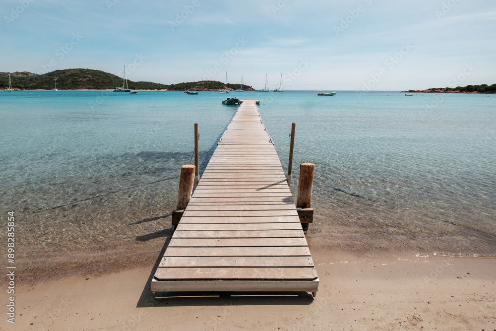 A wooden jetty stretches out into the turquoise Mediterranean sea at Rondinara beach on the island of Corsica A wooden jetty stretches out into the turquoise Mediterranean sea at Rondinara beach on the island of Corsica