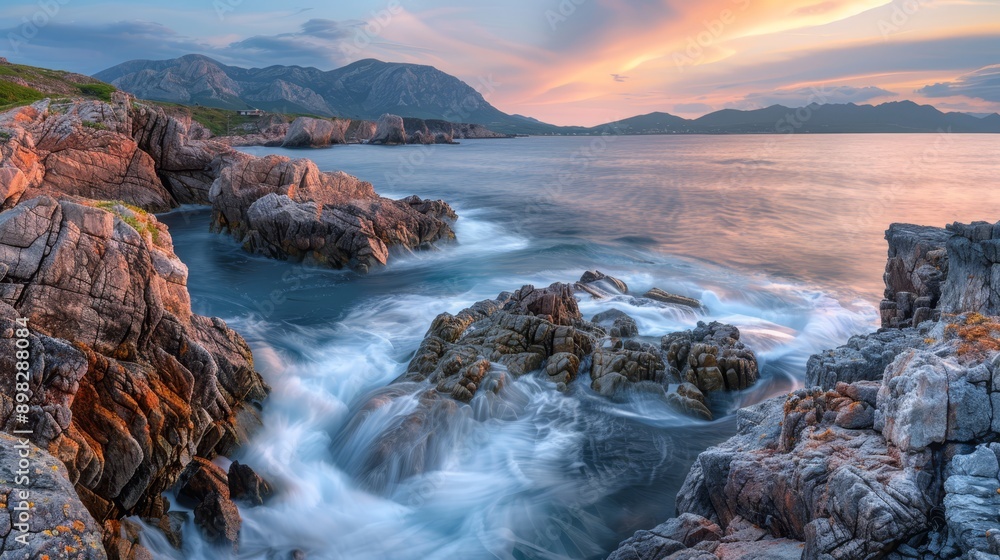 Fototapeta premium A large body of water lies next to a rocky shore, beneath a cloud-studded sky In the distance, mountains loom