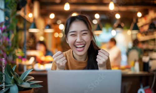 Asian woman in cafe working on laptop while holding blank sign for privacy