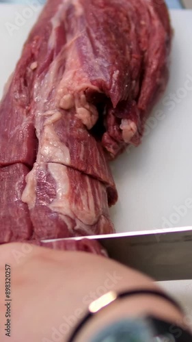 Chef sharpening his knife in front of kitchen table. Cooker preparing his tools before cutting raw pieceof meat and various vegetables Beef tenderloin. Raw beef steak cut photo