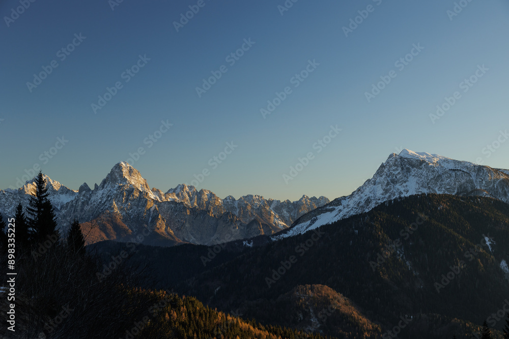 cime e catene montuose innevate lontane di un ambiente naturale di montagna nell'italia nord orientale, al tramonto, in inverno, con un cielo sereno