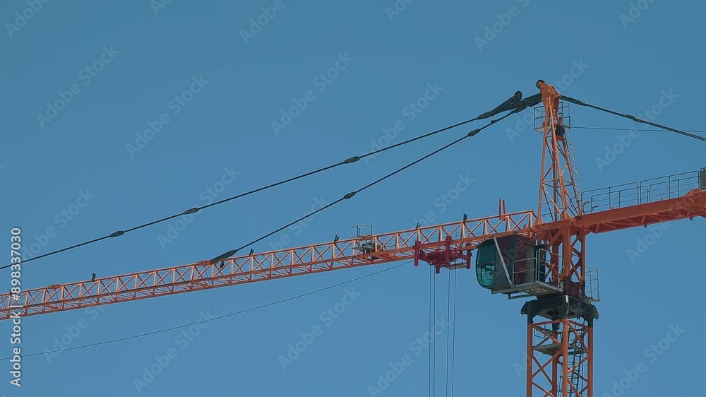 dynamic scene of a construction crane in action against a clear, sunny sky from a low angle dynamic scene of a construction crane in action against a clear, sunny sky from a low angle
