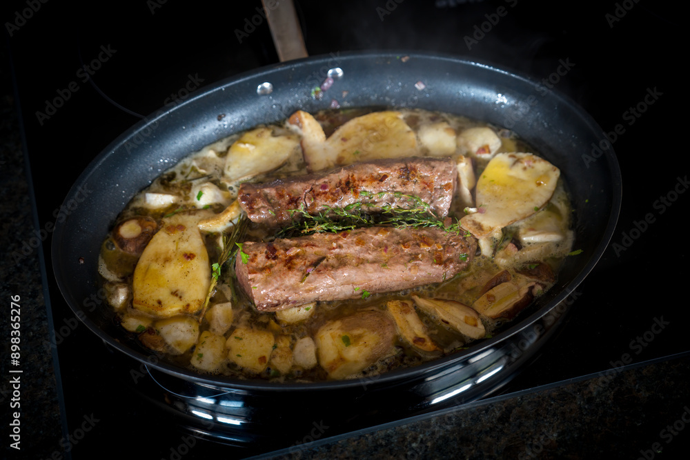 healthy and fres cooking at home - roasted deer tenderloin with and porcini mushrooms, onions, rosemary and thyme in a big pan healthy and fres cooking at home - roasted deer tenderloin with and porcini mushrooms, onions, rosemary and thyme in a big pan