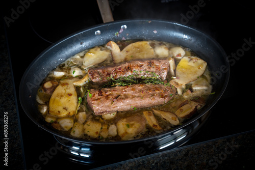 healthy and fres cooking at home - roasted deer tenderloin with and porcini mushrooms, onions, rosemary and thyme in a big pan