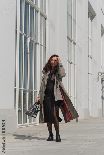 Wallpaper Mural Middle-aged woman walking past a modern white building, enjoying the sunny day. Concept: Reflecting the interaction between urban environments and personal style, emphasizing the beauty of everyday Torontodigital.ca