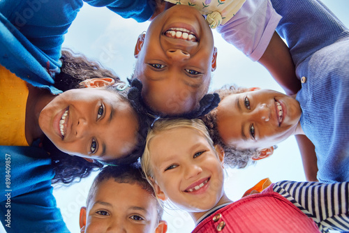 Group of multiethnic children standing in a circle with their heads together photo