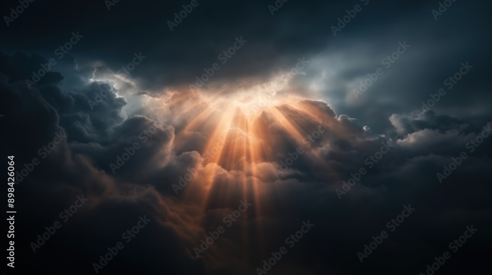 Obraz premium Dramatic sunset rays breaking through dark storm clouds in the sky, creating a striking and contrasting light effect.