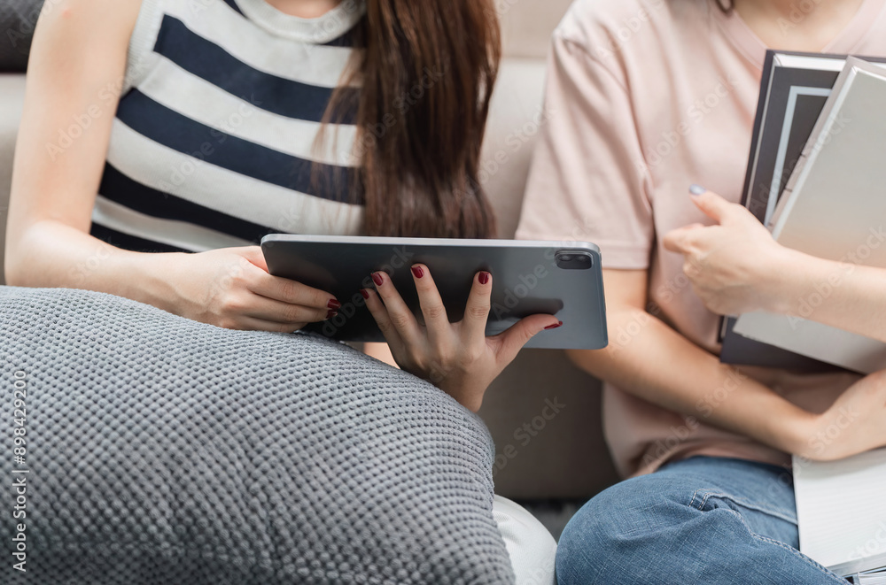 Young Female Friends Studying Together, Helping Each Other Prepare for Exams with Digital Tablet and Books Young Female Friends Studying Together, Helping Each Other Prepare for Exams with Digital Tablet and Books