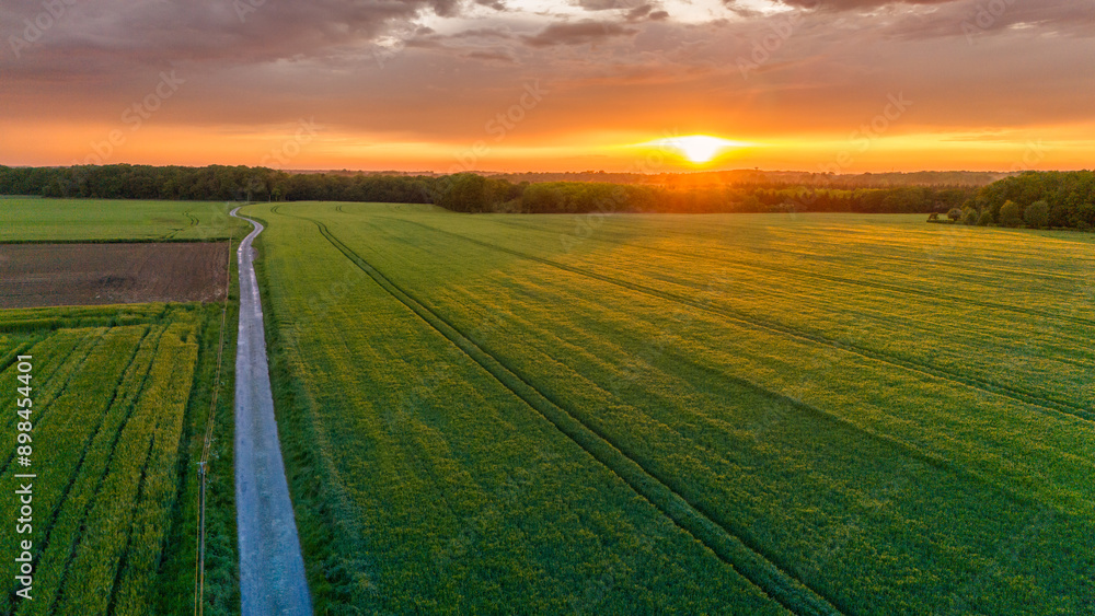 Obraz premium Vue aérienne du coucher de soleil sur fond dramatique très nuageux et orageux au milieu des champs et des forêts du bocage normand en France