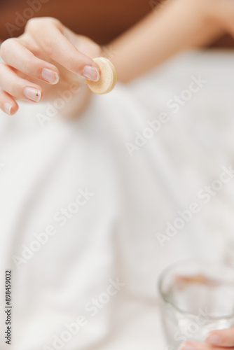 Woman laying in bed with a glass of water and a cookie next to her