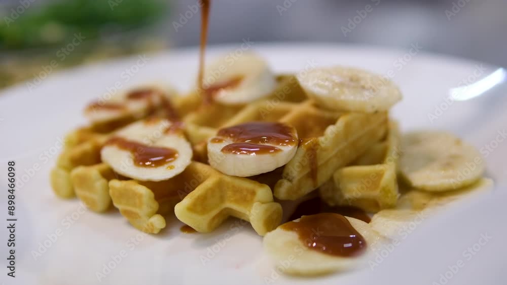 Slow motion pouring honey or maple syrup onto Belgian waffles. Pour caramel onto waffles