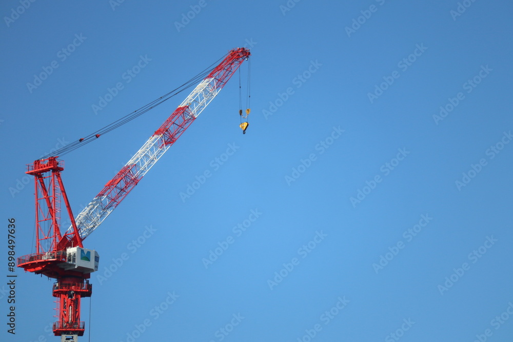 crane on top of a multi-storey building with a clean blue sky background crane on top of a multi-storey building with a clean blue sky background