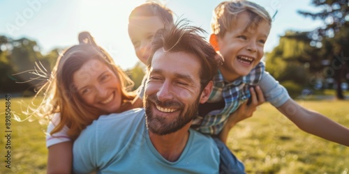 Happy parents piggybacking their kids in a nature park for summer bonding and outdoor family enjoyment. Black father, mother, and children walk on grass smiling.