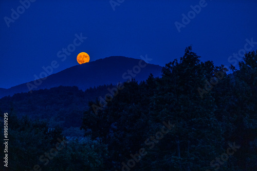 The full flower moon -  07, 2024. The rising moon over the mountain peaks , a cloudless night allows observation of the astronomical phenomenon. 