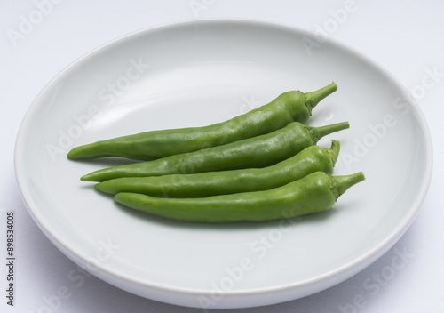 Canvas-taulu Close-up of four fresh green peppers on white dish, South Korea