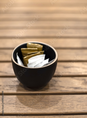 Few bags of white and brown sugar on a wooden coffee table in a cafe