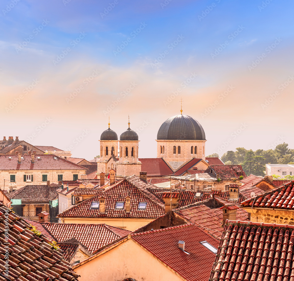 Fototapeta premium beautiful old city sunset landscape with ren and orange tile roofs of houses and nice cathedral church in traditional venetian style with bell tower and chapel and evening sky on background
