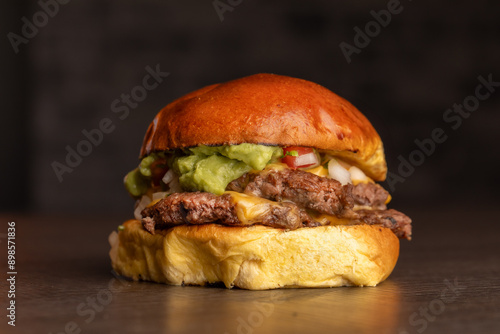 Burger con carne de res, queso,  guacamole, cebolla y tomate con pan brioche