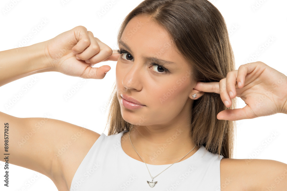Young annoyed woman sticking fingers in ears with eyes open, not listening to loud noise, ignoring stressful environment, stubborn teen refuses hearing, feels ear ache, tinnitus, Young annoyed woman sticking fingers in ears with eyes open, not listening to loud noise, ignoring stressful environment, stubborn teen refuses hearing, feels ear ache, tinnitus,