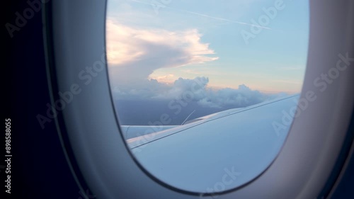 View Through Airplane Window Sunset Sky Fluffy Clouds Wing. Hand Held Camera Plane Warm Light Passenger POV.