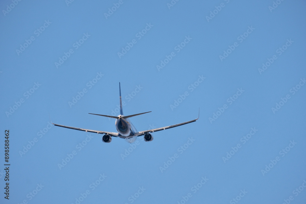 Airplane in Flight Viewed from Behind Against Clear Sky