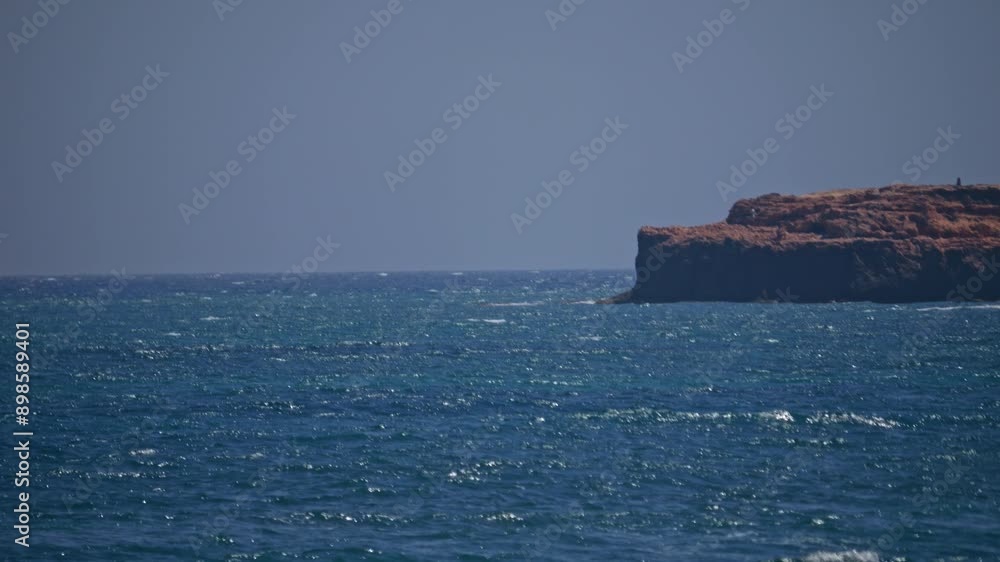 Rocky coastline with a clear blue sea, waves breaking and splashing foam. Slow-motion video, perfect for a holiday scene. Rocky coastline with a clear blue sea, waves breaking and splashing foam. Slow-motion video, perfect for a holiday scene.