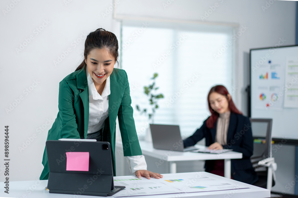 Fototapeta premium A woman in a green jacket is standing in front of a white board with a pink note