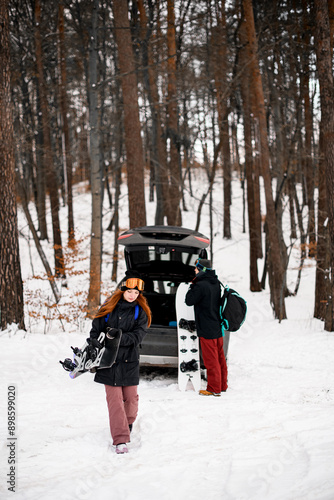 Wallpaper Mural Two young people take snowboards out of the trunk of their car. parked in the winter forest. Torontodigital.ca