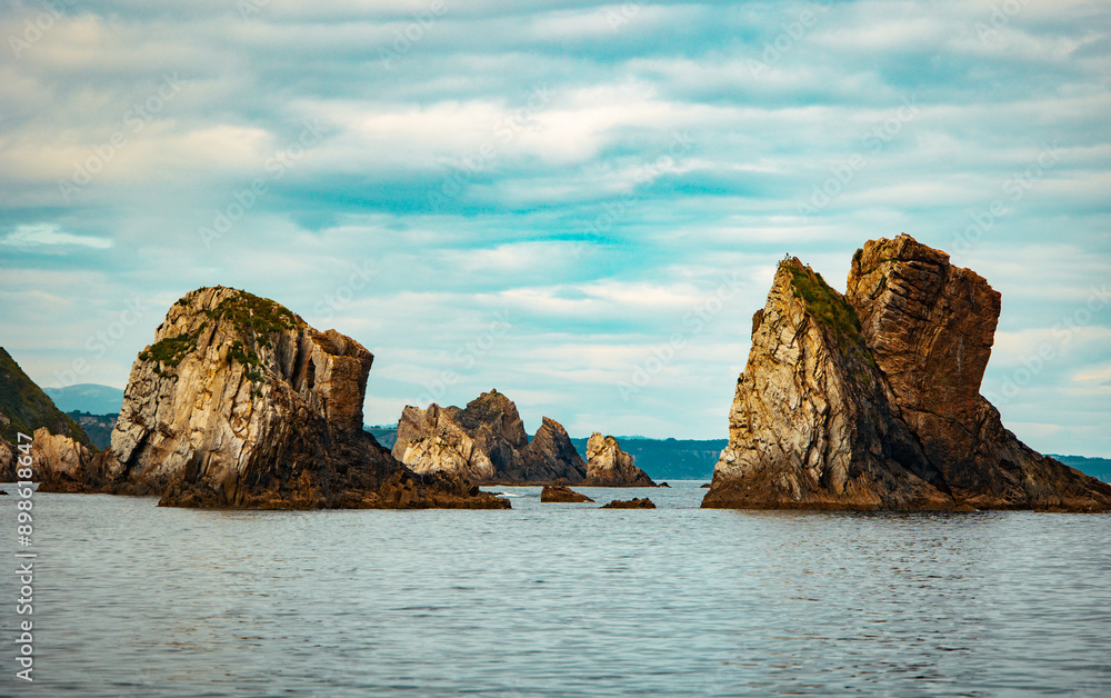 Fototapeta premium Majestic sea stacks rising from calm ocean water under a cloudy sky
