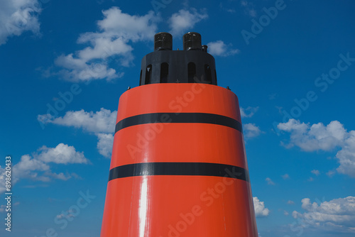 Red and black funnel smoke stack of legendary luxury ocean liner cruise ship against deep blue sky during cruise transatlantic passage in summer photo