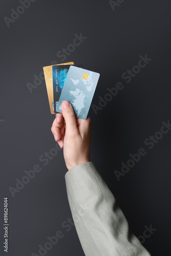 Woman holding credit cards on black background, closeup