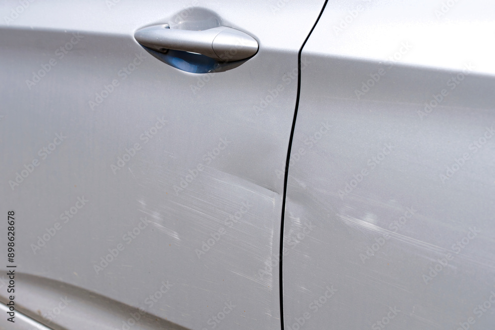 Scratches and dents on car door, damaged paint surface after side impact, resulting from minor collision or accident. Common cosmetic issues that affect the vehicle's appearance