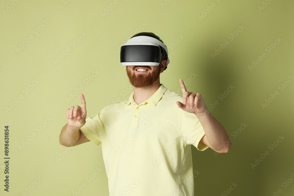 Smiling man using virtual reality headset on pale green background Smiling man using virtual reality headset on pale green background