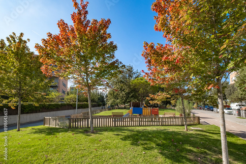 Bright, vibrant park with children's playground featuring slides, benches, and surrounded by lush green grass and trees, perfect for community recreational activities Sant Cugat in Spain photo