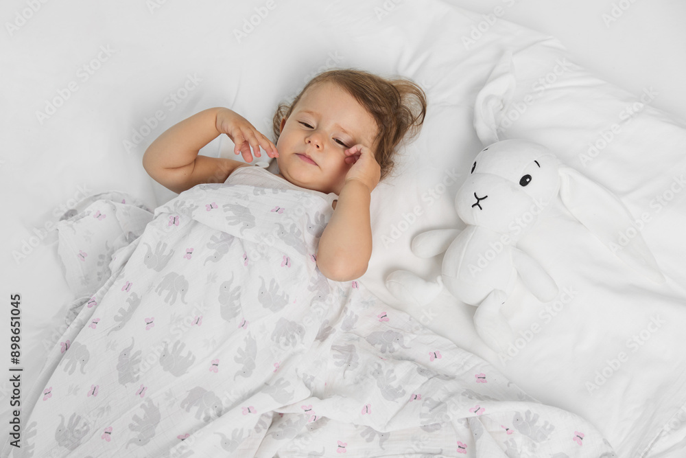 Top view of a cute baby girl, lying on a bed, want to sleep near her toy. Top view of a cute baby girl, lying on a bed, want to sleep near her toy.