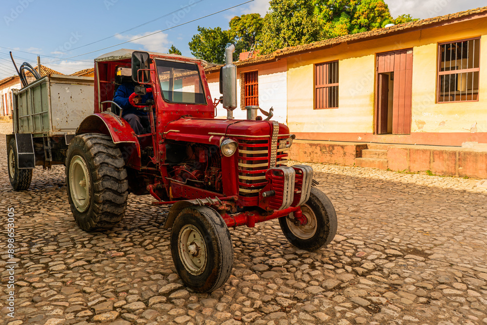 old classic red tractor crossing colonial old downtown in trinidad cuba  