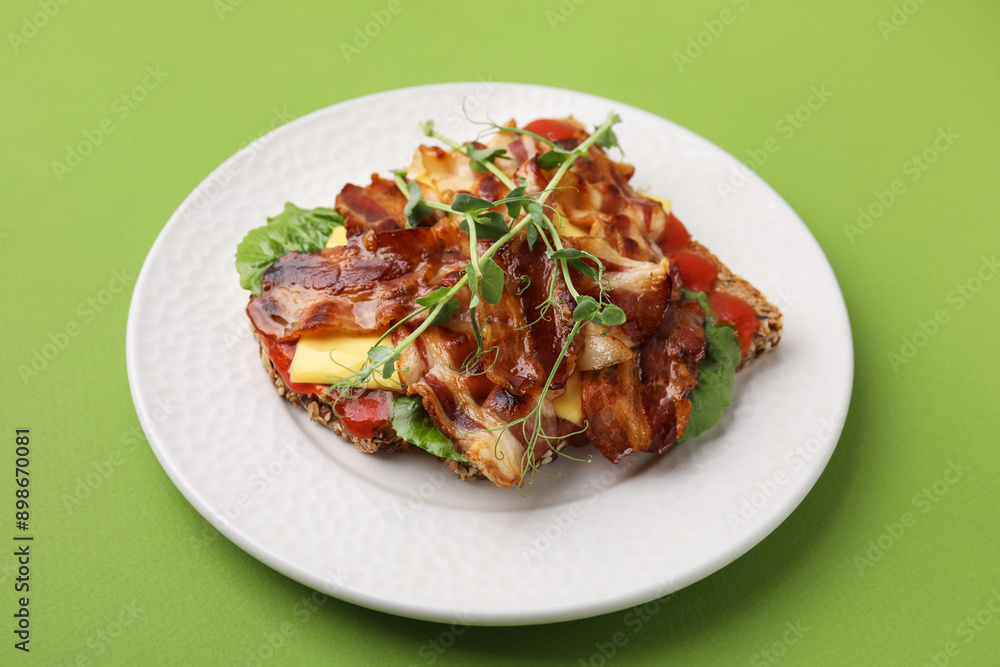 Tasty sandwich with bacon and microgreens on green table Tasty sandwich with bacon and microgreens on green table