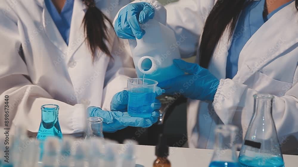 Close-up of a scientist's hands holding a flask with pink liquid in a lab. Close-up of a scientist's hands holding a flask with pink liquid in a lab.
